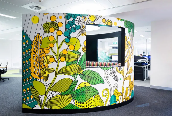 A round sitting booth with a window with the wall wrapped with graphics.